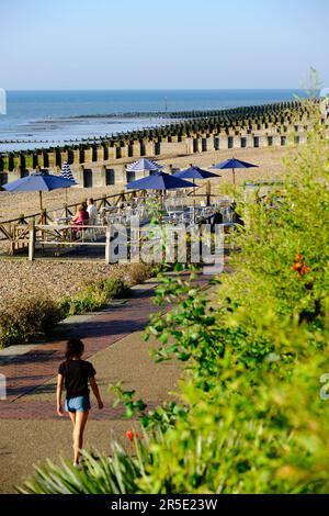 Eastbourne, East Sussex, Regno Unito - Settembre 8 2021: Donna che cammina sul lungomare in una giornata di sole con il ponte caffè sullo sfondo. Foto Stock