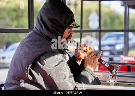 Sousse, Tunisia, 22 gennaio 2023: Vecchio flauto arabo, vestito caldo e impermeabile, in un treno passeggeri aperto per l'intrattenimento del passe Foto Stock