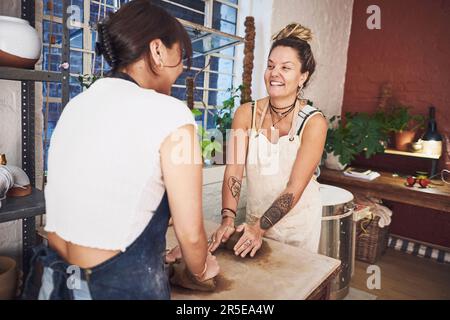 I migliori amici non ti lasciano prendere lezioni di ceramica da solo. due giovani donne impastano l'argilla in uno studio di ceramica. Foto Stock