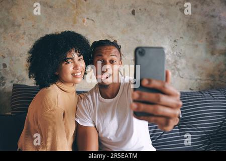 Non smettere mai di fare ricordi divertenti insieme. una giovane coppia che prende selfie insieme a casa. Foto Stock