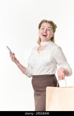 Donne ecstatic shopaholic che tengono il telefono delle cellule e le borse di shopping con gli acquisti. L'etnia caucasica la bionda ride gioiosamente. Vendita Black Friday Foto Stock