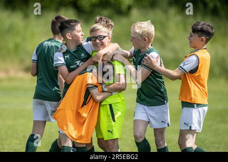 I ragazzi che giocano hanno organizzato partite di football e calcio di base nel Regno Unito nelle giornate di sole. Foto Stock