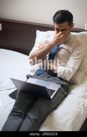 L'uomo stanco sta lottando con il sonno mentre lavora sui documenti Foto Stock