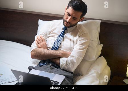 L'uomo stanco nei vestiti dell'ufficio si è addormentato mentre lavora ai documenti Foto Stock