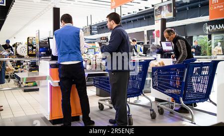 Aiuto a portata di mano: Il personale del supermercato aiuta i clienti al check-out automatico Foto Stock