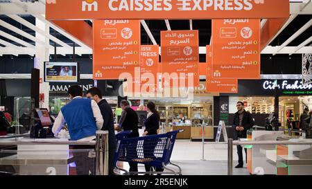 Il personale del supermercato guida i clienti attraverso il self-checkout Foto Stock