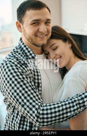Allegro uomo portatore che abbraccia teneramente la moglie Foto Stock