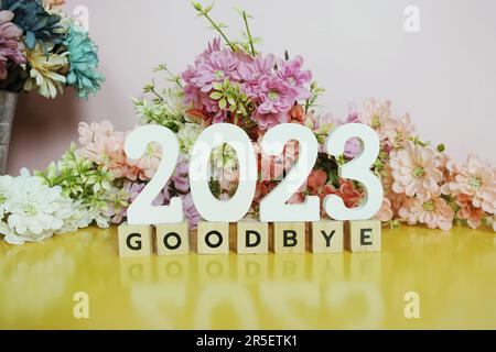 Addio 2023 lettere alfabetiche con decorazione floreale su sfondo rosa e giallo Foto Stock