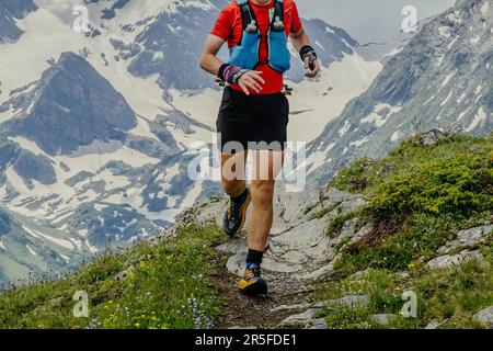 atleta runner pista di montagna skyrunning maratona in background picchi innevati, jogging percorso difficile gara Foto Stock