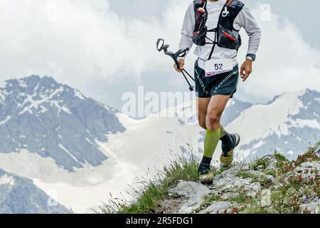 atleta runner pista di montagna corsa skyrunning sul bordo della scogliera, bastoni da trekking in mano Foto Stock