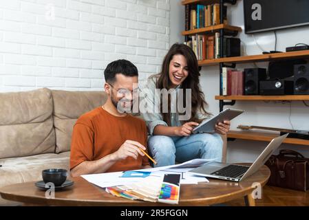 Coppia di architetti che lavorano alla ristrutturazione degli interni sul posto di lavoro. I progettisti scelgono i campioni di colore in base alla visualizzazione e alle blueprint del p Foto Stock