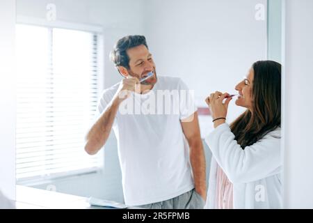 Il primo che ride è il perdente. una coppia spazzolando i denti nel bagno a casa. Foto Stock