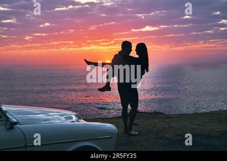 Lui sa come spazzarmi via dai miei piedi. una giovane coppia che fa una sosta in spiaggia mentre fuori in viaggio. Foto Stock