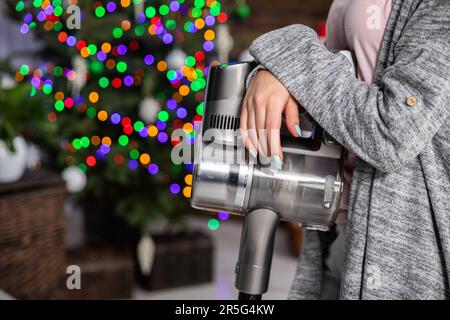 Le mani di una donna appoggiate a un aspirapolvere. Una breve pausa nelle pulizie. Foto Stock