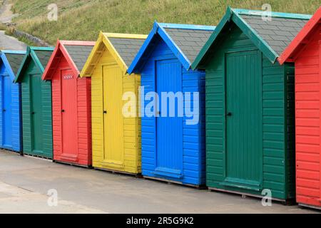 Una fila di capanne colorate lungo il lungomare di Whitby, prese di fronte Foto Stock
