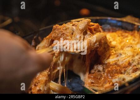 Troppo carico cheesy torta ziti che vengono serviti Foto Stock