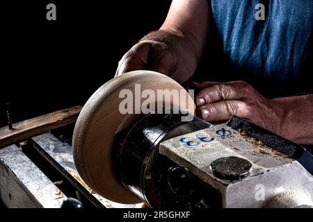 Artigiano che crea una ciotola di legno sul tornio. Immagine nell'officina.sfondo nero. Foto Stock