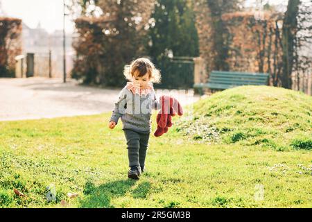 Ritratto all'aperto di adorabile bambina che gioca con il giocattolo rosa coniglietto in un parco verde soleggiato all'inizio della primavera Foto Stock