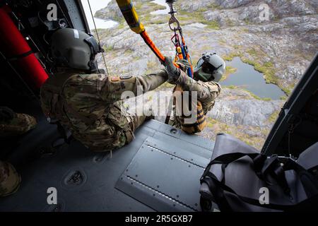 Alaska Army National Guardsmen staff Sgt. Sonny Cooper e Sgt. Billy Bocast lavoro la gru a bordo di un elicottero HH-60L Black Hawk durante una missione di qualificazione del personale aereo e manovre di volo di base di addestramento maggio 31,2023. Il Black Hawk partì dal campo di aviazione militare Bryant sulla base congiunta Elmendorf-Richardson. (Foto della Guardia Nazionale dell'Alaska di Robert DeBerry) Foto Stock