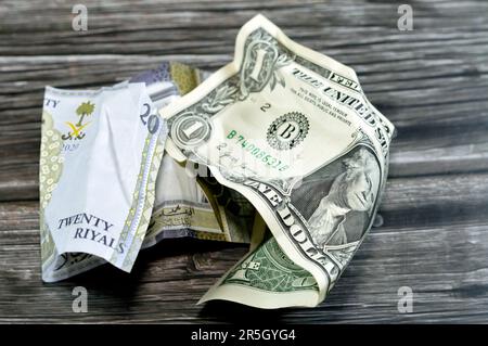 Corrugato e sbriciolato Arabia Saudita denaro di 20 SAR venti riyals e 1 un dollaro americano denaro contante, inflazione di denaro e perdita di valore, concetto di caduta, Foto Stock