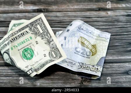 Corrugato e sbriciolato Arabia Saudita denaro di 20 SAR venti riyals e 1 un dollaro americano denaro contante, inflazione di denaro e perdita di valore, concetto di caduta, Foto Stock
