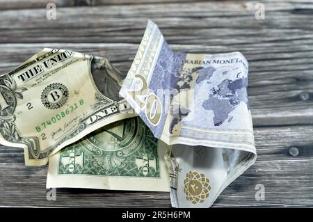 Corrugato e sbriciolato Arabia Saudita denaro di 20 SAR venti riyals e 1 un dollaro americano denaro contante, inflazione di denaro e perdita di valore, concetto di caduta, Foto Stock