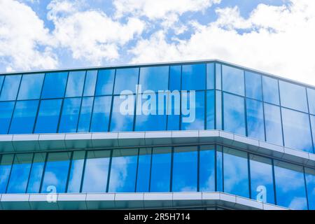 Futuristica Torre di vetro con una splendida facciata blu e nuvole bianche nel cielo Foto Stock