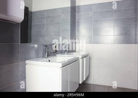 Lavandino bello e pulito vicino allo specchio nel bagno pubblico Foto Stock