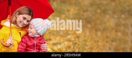 Madre e figlia con ombrello nel parco autunnale il giorno delle piogge, spazio per il testo. Design del banner Foto Stock