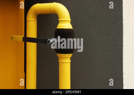 Tubo di gas giallo vicino alla parete marrone all'esterno Foto Stock