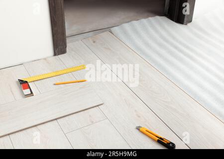 Attrezzi di riparazione e tavole di parquet sul pavimento in camera Foto Stock