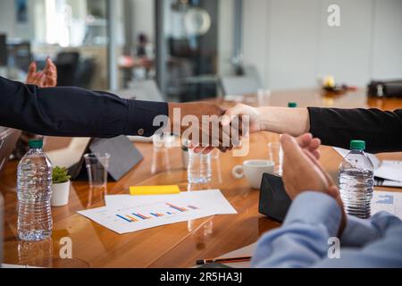 Durante una riunione in una sala conferenze, è possibile fare una stretta di mano tra due persone di diverse etnie. Foto Stock