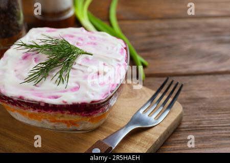 Aringa sotto pelo su tavolo di legno, spazio per il testo. Insalata russa tradizionale Foto Stock