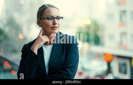 Prende i sogni e li trasforma in realtà. una donna d'affari matura in piedi fuori sul balcone del suo ufficio aziendale. Foto Stock