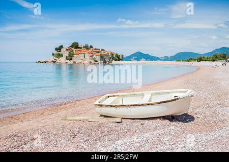 Una piccola barca da pesca vista sulla spiaggia di Ivano Vidoni di fronte alla bellissima isola di Sveti Stefan in Montenegro nel maggio 2023. Foto Stock