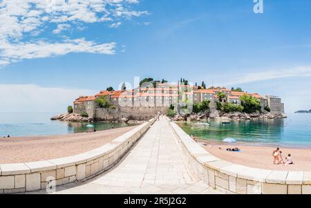 Un panorama a più immagini che si affaccia sulla strada sopraelevata verso l'isola di Sveti Stefan in Montenegro, circondato da alcuni amanti della spiaggia nel maggio 2023. Foto Stock