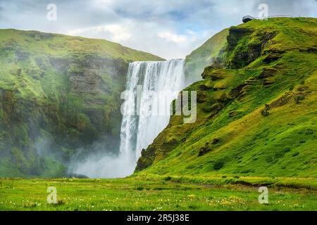Splendido scenario della lussureggiante cascata Skogafoss che scorre in estate nel sud dell'Islanda Foto Stock