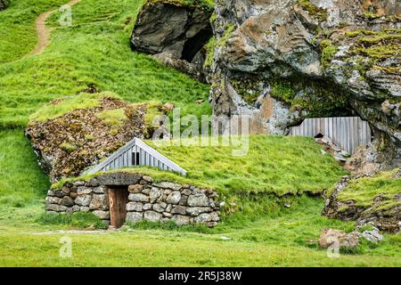 Rutshellir Grotte Cottage in erba con tetto le antiche abitazioni nella montagna rocciosa in estate in Islanda Foto Stock