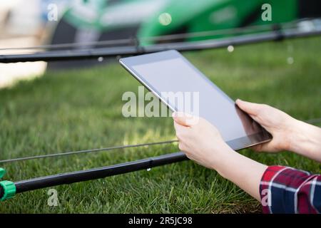 Il contadino controlla il sistema di irrigazione a goccia con tablet digitale Foto Stock