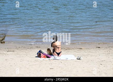 Rodenkirchen, Germania. 04th giugno, 2023. Una signora si siede sulle rive del Reno e gode del clima caldo con il sole, altre persone rinfrescarsi nelle fresche acque del fiume. I meteorologi prevedono il tempo estivo per tutta la settimana successiva. Credit: Roberto Pfeil/dpa/Alamy Live News Foto Stock