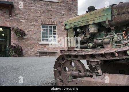 Vecchio trattore cingolato rasty davanti all'edificio in mattoni Foto Stock