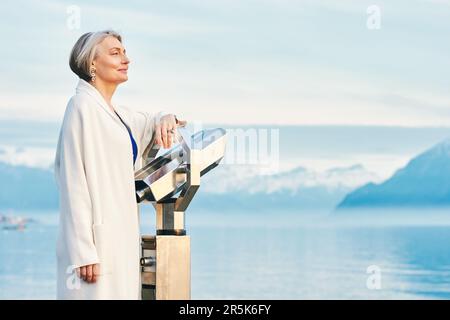 Bella donna di mezza età ammirando la vista incredibile del lago d'inverno e delle montagne Foto Stock