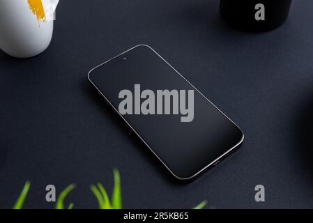 Telefono vuoto sul tavolo nero. Pianta, tazza di caffè e penne possono accanto. Posizione professionale Foto Stock