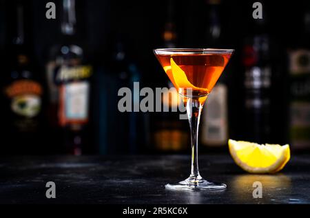 Cocktail alcolico Bobby Burns con whisky scotch, vermouth e liquore in vetro martini, sfondo del banco del bar scuro Foto Stock