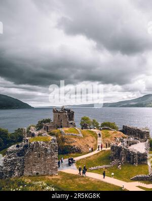 Adagiato sulle rive del Loch Ness, un castello sorge con orgoglio sullo sfondo delle tranquille acque. Le sue antiche pareti in pietra echeggiano con racconti di hi Foto Stock