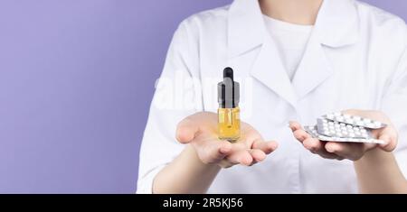 In un palmo di una dottoressa ci sono bottiglie di estratto di olio di cbd, nell'altro palmo ci sono diversi blister di compresse. Alternativa può medico Foto Stock