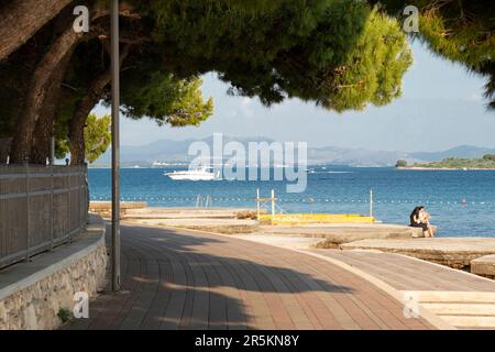 Vodice, Croazia - 27 maggio 2023: Passeggiata con pinete ombra al mare e persone e barche in lontananza, in preason Foto Stock