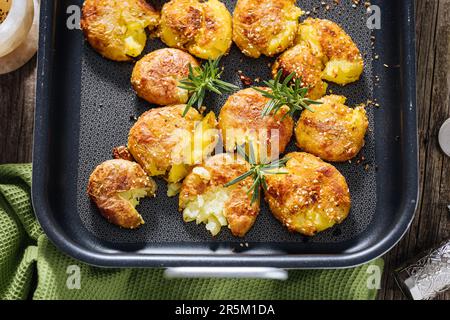 Patate al forno o arrosto in vassoio di metallo condito con rosmarino e sale e pepe. Dorato e croccante. Foto Stock