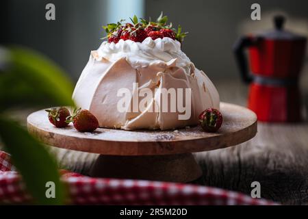 Pavlova torta decorata con fragole su rustico tavolo di legno. La torta è fatta di meringa e panna montata Foto Stock