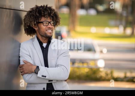 Uomo d'affari nero positivo in tuta posa da centro ufficio, dopo una pausa dopo una riunione di lavoro di successo, fotocopiatrice spazio Foto Stock